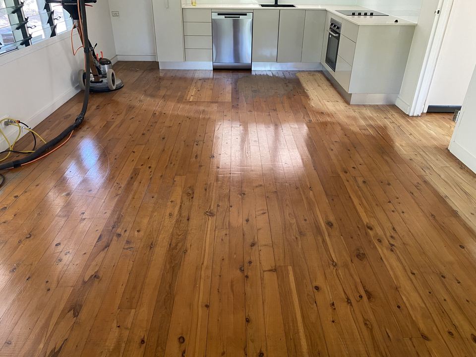 Floor sanding machine on a freshly coated pine floor in a kitchen.